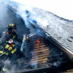 Fire fighter putting out roof on fire